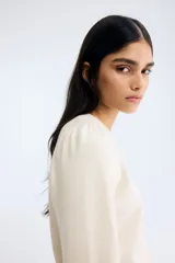 Sweater de punto suave color beige, con cuello redondo, mangas largas con frunces en los hombros y terminaciones acanaladas en cuello, puños y bajo.