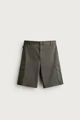 Bermuda cargo color verde militar de corte relaxed fit, confeccionada en tejido de algodón. Cuenta con bolsillos laterales con solapa en las perneras, trabillas en la cintura con ajuste lateral y cierre frontal con cremallera y botón.