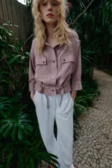 Chaqueta corta marrón de cuello solapa y manga remangada por debajo del codo. Presenta bolsillos delanteros de plastrón con solapa, bajo ajustable con cordón interior y cierre frontal con botones.