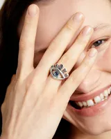 Anillo plateado en forma de ojo con cristal facetado azul.