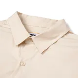 Camisa de manga larga color arena con cuello clásico, cierre frontal con botones, dos bolsillos de parche en el pecho con solapa y logo de Caterpillar en el bolsillo derecho.