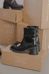 Bota de caña media con punta cuadrada, confeccionada en cuero gamuzado color marrón, con taco bloque y suela de goma negra.