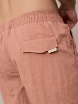 Short de baño azul marino con cintura elástica ajustable con cordón y logo de la marca bordado en rojo en la pierna izquierda.