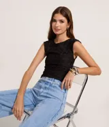 Blusa sin mangas de color negro, confeccionada en poliéster con textura en relieve, cuello redondo y corte al cuerpo.