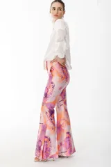 Pantalón de vestir con leve evasé y tajo en laterales, con estampado de flores grandes en tonos violeta y naranja.