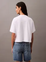 Remera blanca de algodón con corte cropped y mangas cortas. Presenta un estampado fotográfico floral de Calvin Klein en el lateral.