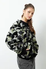 Campera polar con estampado camuflado en tonos verde, gris y negro. Cuenta con cierre frontal, puños elastizados a tono y capucha.