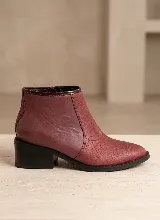 Bota corta de cuero vacuno en color bordó, con diseño combinado de cuero liso y textura de reptil. Cuenta con taco cuadrado de 5 cm, suela de caucho antideslizante y cierre lateral.