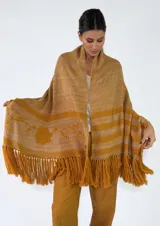 Pashmina de punto color beige con bordados sutiles y flecos largos en los bordes.