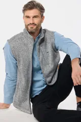 Chaleco de felpa gris con textura jaspeada, cuello alto y detalle de etiqueta de cuero sintético en la nuca.