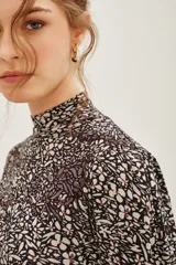 Polera de manga larga con cuello alto, confeccionada en tejido de algodón con estampado floral tipo liberty en tonos oscuros.