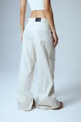 Pantalón sastrero de gabardina color beige, con pinzas delanteras, presillas anchas en la cintura y tajo interno en la botamanga.