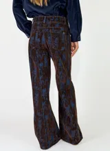 Pantalon de corte recto y tiro alto, confeccionado en tela con textura tipo pana o denim con un estampado abstracto en tonos marrones y azules.