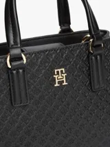 Cartera tote negra de poliuretano con acabado texturizado, motivo integral del monograma TH en bajo relieve, insignia metálica dorada en el frente, dos asas superiores y correa cruzada extraíble.
