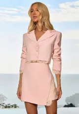 Falda corta de mujer color rosado, con diseño cruzado (envelope) y sutiles detalles de encaje beige en el borde inferior.