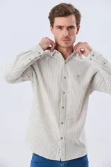 Camisa de lino rayada de manga larga, con cuello camisero, cierre frontal de botones y bordado sutil en el pecho.