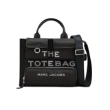 Bolso tipo tote Marc Jacobs modelo The Cargo Canvas Medium, color negro. Confeccionado en lona resistente, cuenta con asas superiores, correa ajustable para el hombro y múltiples bolsillos delanteros externos. Presenta el texto "THE TOTE BAG" y el logo de la marca bordados en el frente.