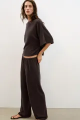 Top blanco de tejido rústico, con cuello redondo y mangas cortas amplias. Bajo recto.