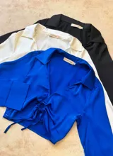 Top corto negro con escote en V, mangas largas y lazo ajustable en el centro.