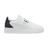 Championes urbanos Puma modelo Shuffle Downtown, de diseño clásico y perfil bajo. Presentan una capellada blanca con detalles en negro en la zona del talón y el logo de la marca en dorado. Cuentan con suela de goma y sistema de cordones.