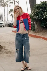 Chaqueta de punto con cuello redondo y manga larga. Presenta un diseño color block con el pecho en rojo, la parte inferior en azul y mangas a rayas horizontales en rosa y rojo. Cierre frontal con botones.