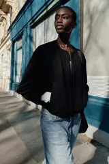 Chaqueta bomber de cuello redondo y manga larga con diseño holgado. Presenta cierre frontal con cremallera, bolsillos delanteros de vivo y acabados elásticos en los puños y el ruedo.