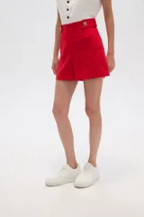 Short de lino color beige, de tiro alto y corte holgado. Presenta bolsillos frontales amplios y detalle de botones decorativos en la cintura.