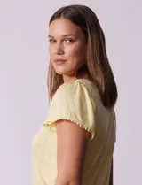 Remera tejida con estampado animal print, de manga corta con detalle de puntilla en las mangas y cuello redondo.