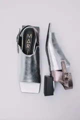 Sandalias de cuero color marrón con puntera abierta, talón descubierto y tira trasera con hebilla. Taco bajo de madera.