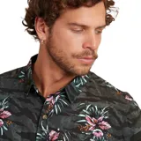 Camisa de manga corta para hombre Maui and Sons, con estampado de flores y hojas sobre fondo con diseño de camuflaje. Tiene cuello clásico, cierre frontal con botones y bolsillo en el pecho.