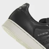 Championes Adidas Superstar II de color negro con la icónica puntera de caucho en relieve y suela blanca. Presenta detalles con estampado de piel de serpiente en las tres tiras laterales y en el talón, además de cordones blancos y el nombre del modelo en dorado.
