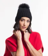 Gorro negro de punto acanalado con bajo plegado y pompón de pelo sintético en la parte superior.