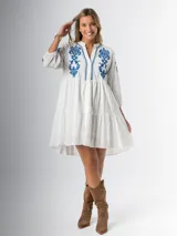 Vestido corto blanco de algodón italiano con bordado azul, mangas tres cuartos y botones frontales. Tiene forro interior en la falda.