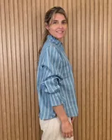Blusa rosada de algodón con delicados bordados florales blancos, escote en V con cuello elevado y volados, y mangas largas con puños acampanados.