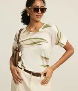Blusa estilo remera de cuello redondo y manga corta, confeccionada en viscosa con estampa de follaje en tonos verdes y rosados sobre base blanca.