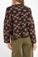 Sweater de punto con diseño de cuadros en tonos marrón y beige, de corte recto, cuello redondo y manga larga.