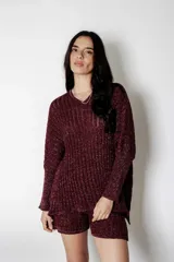 Poncho tejido en lurex color bordó, con textura acanalada y brillo. Presenta un calce suelto y relajado.