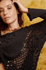 Sweater negro de algodón tejido a mano con apliques de crochet en los laterales y cuello bote amplio.