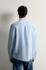 Camisa regular fit celeste confeccionada en mezcla de lino y algodón, con cuello abotonado, manga larga, bolsillo frontal en el pecho y cierre de botonadura.
