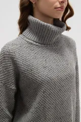 Polera de tejido de punto con cuello alto, diseño holgado y mangas largas. Presenta una textura de relieve tipo waffle en color natural.