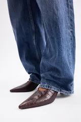 Zapato destalonado de cuero vacuno con textura efecto cocodrilo, diseño de punta fina y taco bajo.