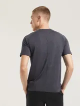 Camiseta deportiva de manga corta con diseño jaspeado, cuello redondo y dobladillo curvo. Presenta un pequeño logo reflectante en la parte inferior.