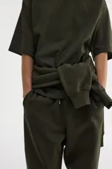 Remera de algodón pesado color verde oscuro, con cuello redondo ribeteado, hombros caídos y corte oversized.