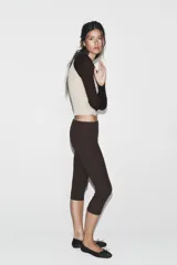 Camiseta de manga larga, corte slim fit, con cuerpo color beige claro y mangas y cuello polo en color marrón oscuro. Presenta un escote en pico bajo el cuello polo.