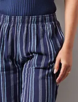Pantalón de algodón estampado a rayas verticales azules y blancas, marca Erika. Tiene pretina elastizada, bolsillos delanteros, ruedo lateral con tajo y botones decorativos.
