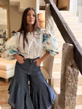 Camisa de popelina con cuerpo central blanco y mangas abullonadas con estampado floral en tonos celestes y marrones, cuello redondo y cierre frontal de botones.