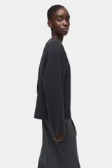Buzo oversized de punto interlock pesado en color negro, con cuello redondo y mangas largas amplias.