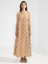 Vestido largo de corte fluido con escote en V profundo y finos breteles. Presenta un estampado animal print combinado con rayas y un detalle decorativo de flor en cobre en el centro del escote.