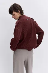 Cardigan de punto acanalado en color bordó, con cuello polo y cierre frontal de botones. Presenta un diseño de hombros caídos y mangas largas con puños ajustados.