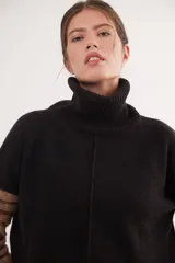 Polera de calce relajado con cuello alto, confeccionada en lana. Presenta un diseño bicolor con cuerpo en gris claro y mangas con estampado jacquard de arabescos en tonos tierra y negro. Incluye detalle de costura central vertical en el frente.